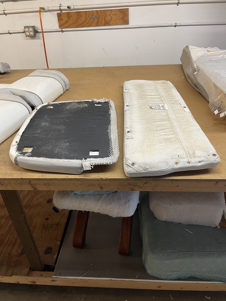 Existing seat cushions turned over for inspection on the workbench